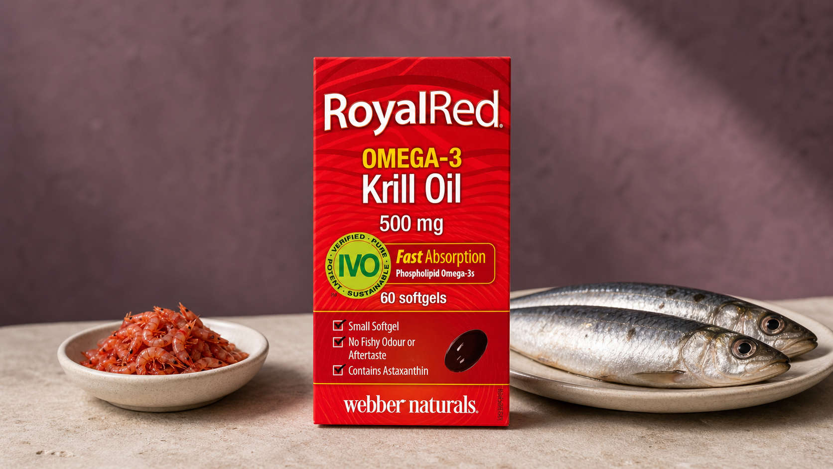 Červené balenie Webber Naturals RoyalRed Omega-3 Krill Oil 500 mg na svetlom kamennom podklade vedľa misky s krilom a taniera s dvoma sardinkami.